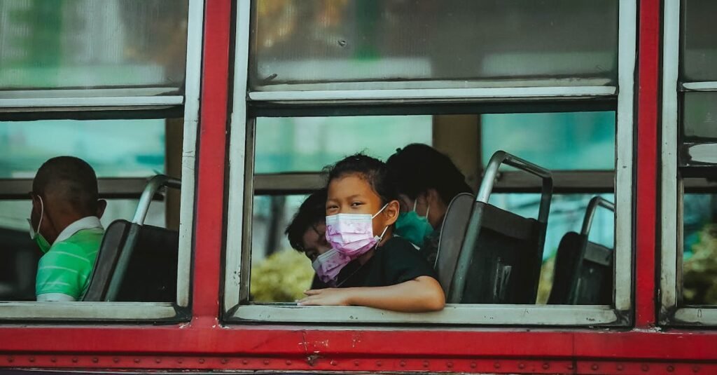 A young child wearing a face mask on a bus in Bangkok, Thailand, highlighting public transportation during pandemic times.