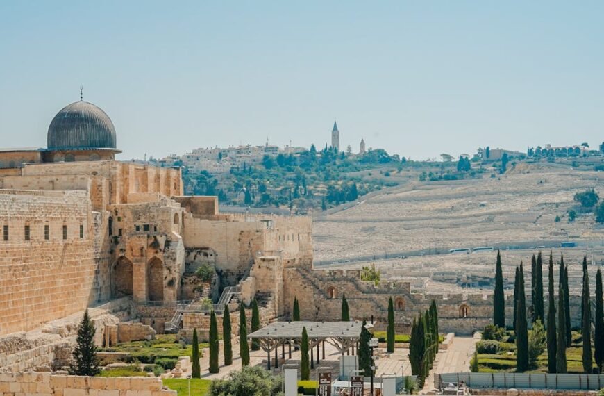 View of the historic Jerusalem walls and Al-Aqsa Mosque with a clear blue sky backdrop.